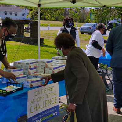 A woman picks up a COVID home test kit at an outdoor event at Philippi Missionary Baptist Church in Simpson, a community partner in Pitt County (NC)
