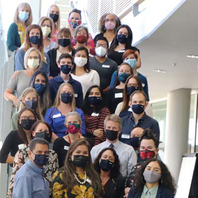 Diverse group of researchers wearing masks posing on stairs.