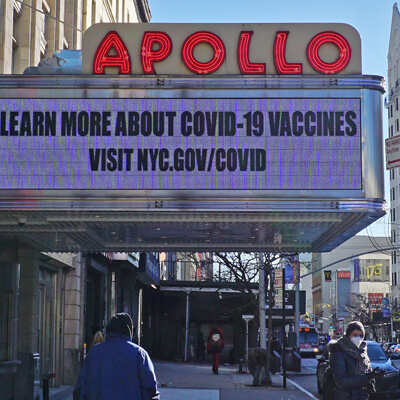 In Harlem, the Apollo Theater marquee says Learn more about covid-19 vaccines, visit nyc.gov/COVID