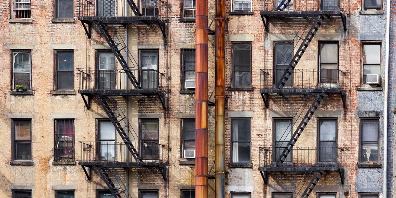 Old apartment building with rusted metal pipes.