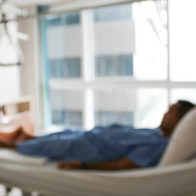 Blurred photo of a Black, male patient sleeping in a hospital bed