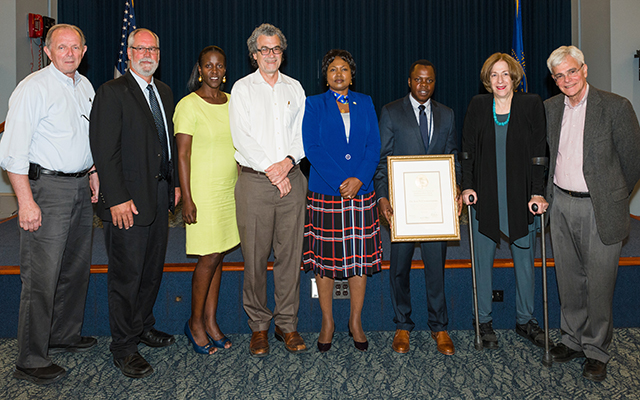 Dr. Utumatwishima poses for a picture with his NIH plaque and those involved with the NIH Rwanda fellowship program