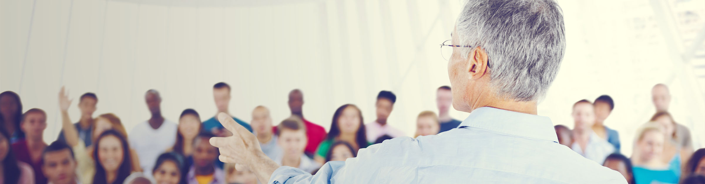 An older man gestures as he speaks to an audience