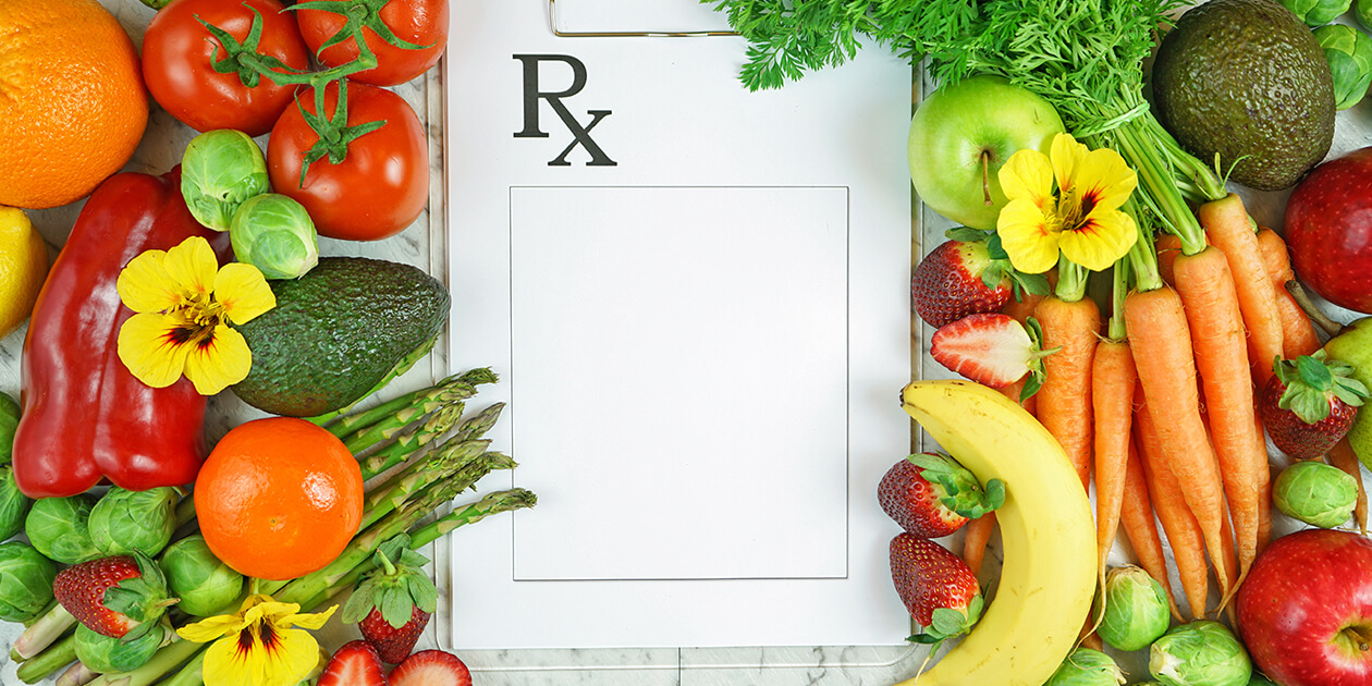 Colorful fruits and vegetables surround an RX pad