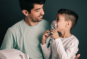Hispanic or Latino man and boy with inhaler 