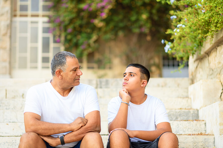 Father and son sitting on steps having a deep discussion.