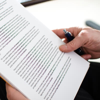 A hand holding a pen and a document in a position to read it