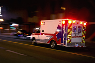 An ambulance speeding through traffic at night.