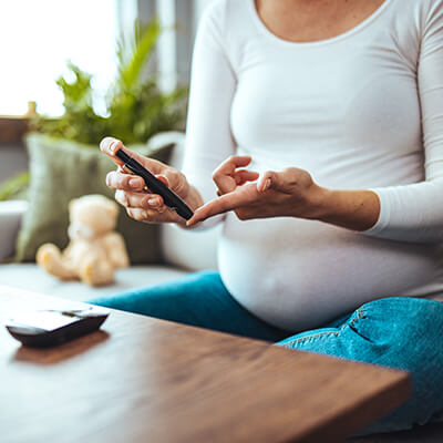Image of a pregnant person testing their blood sugar to depict the subjects of the research study.
