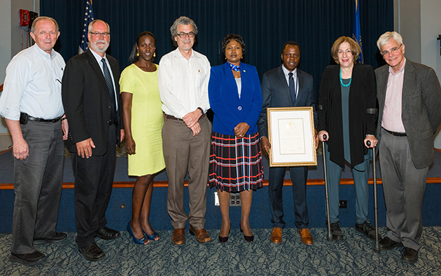 Dr. Utumatwishima poses for a picture with his NIH plaque and those involved with the NIH Rwanda fellowship program. (L-R) NIDDK Clinical Director of Intramural Research Dr. James Balow, NIDDK Scientific Director of Intramural Research Dr. Michael Krause, Dr. Margaret Udahogora from the University of Maryland, NIMHD Director Dr. Eliseo J. Pérez-Stable, Ambassador of the Republic of Rwanda Professor Mathilde Mukantabana, Dr. Jean Nepo Utumatwishima, Dr. Anne Sumner of NIDDK, and NIH Deputy Director for Intramural Research Dr. Michael Gottesman.